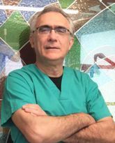 Un hombre con un matorral verde está de pie con los brazos cruzados frente a una vidriera.
