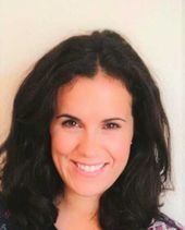 Una mujer con cabello largo y oscuro sonríe para la cámara.