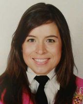 Una mujer que lleva una chaqueta rosa y una corbata negra sonríe a la cámara.