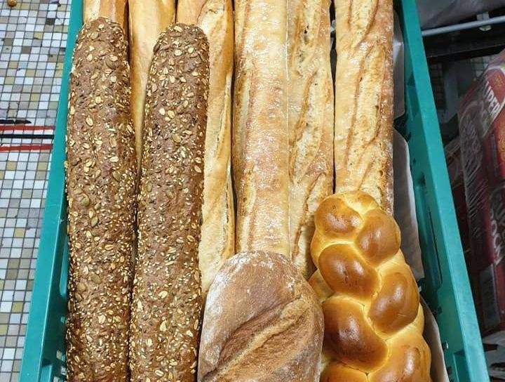 Baguettes assorties et pains tressés présentés dans une vitrine de boulangerie.