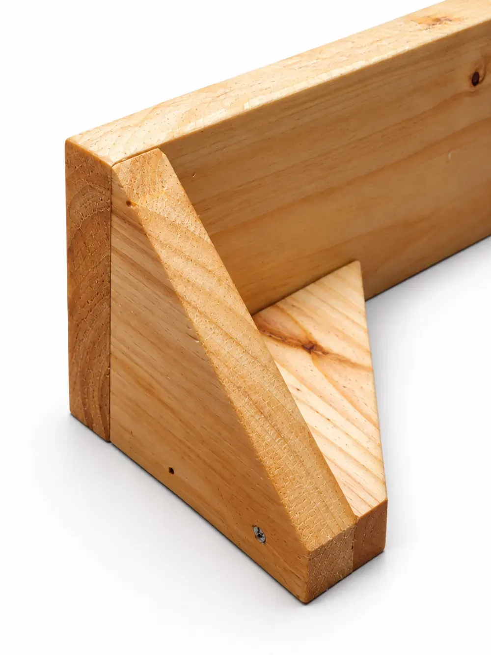 Unión de esquina de madera con refuerzo triangular y tornillos, en un primer plano de una estructura de carpintería.
