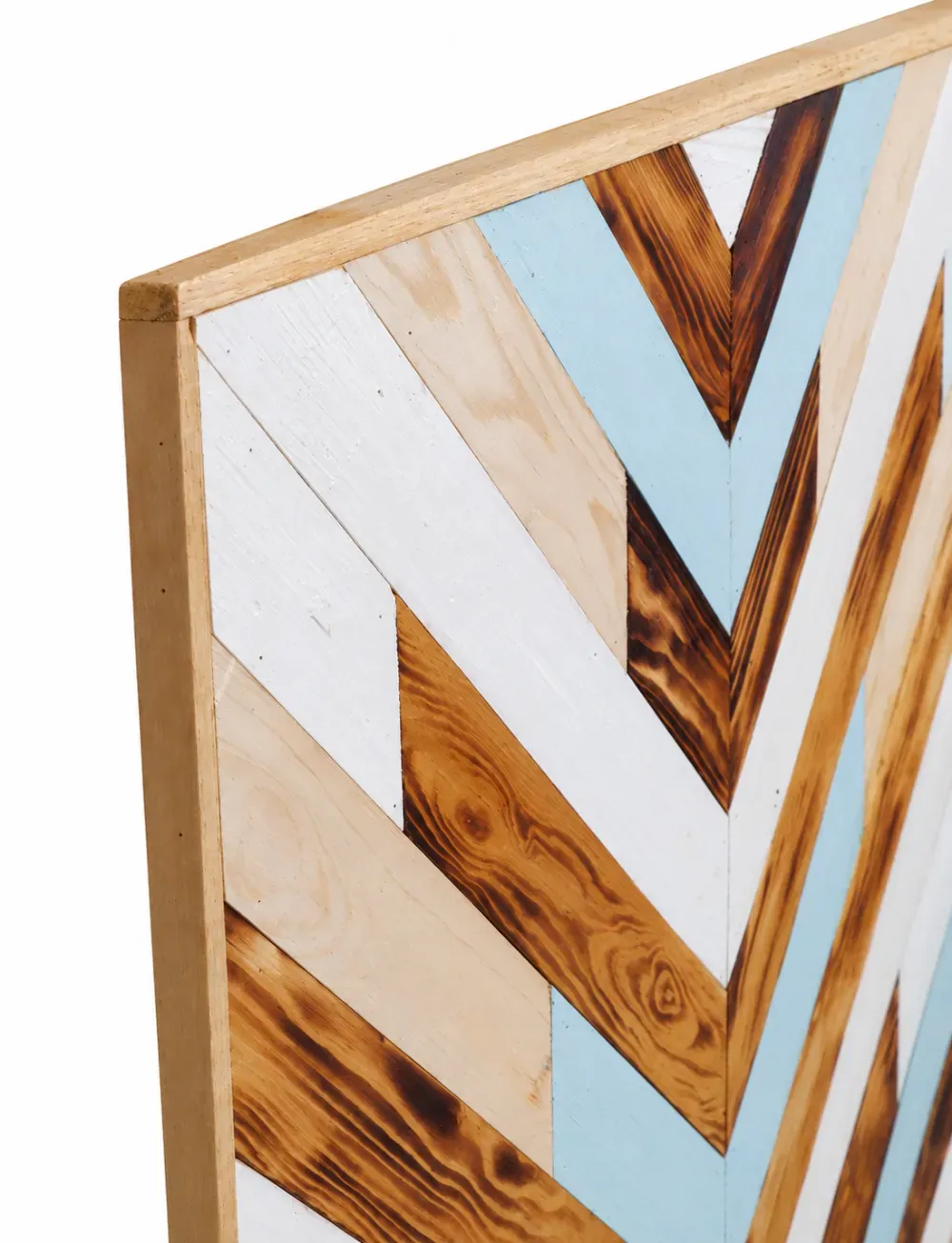 Primer plano de un panel decorativo de pared de madera con diseño de espiga y detalles en blanco, azul y madera teñida