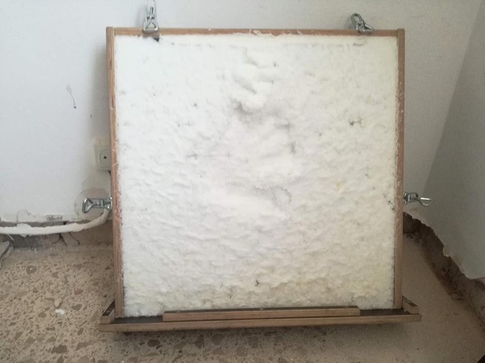 Tablero de espuma blanca con marco de madera apoyado contra la pared en la esquina de una habitación.