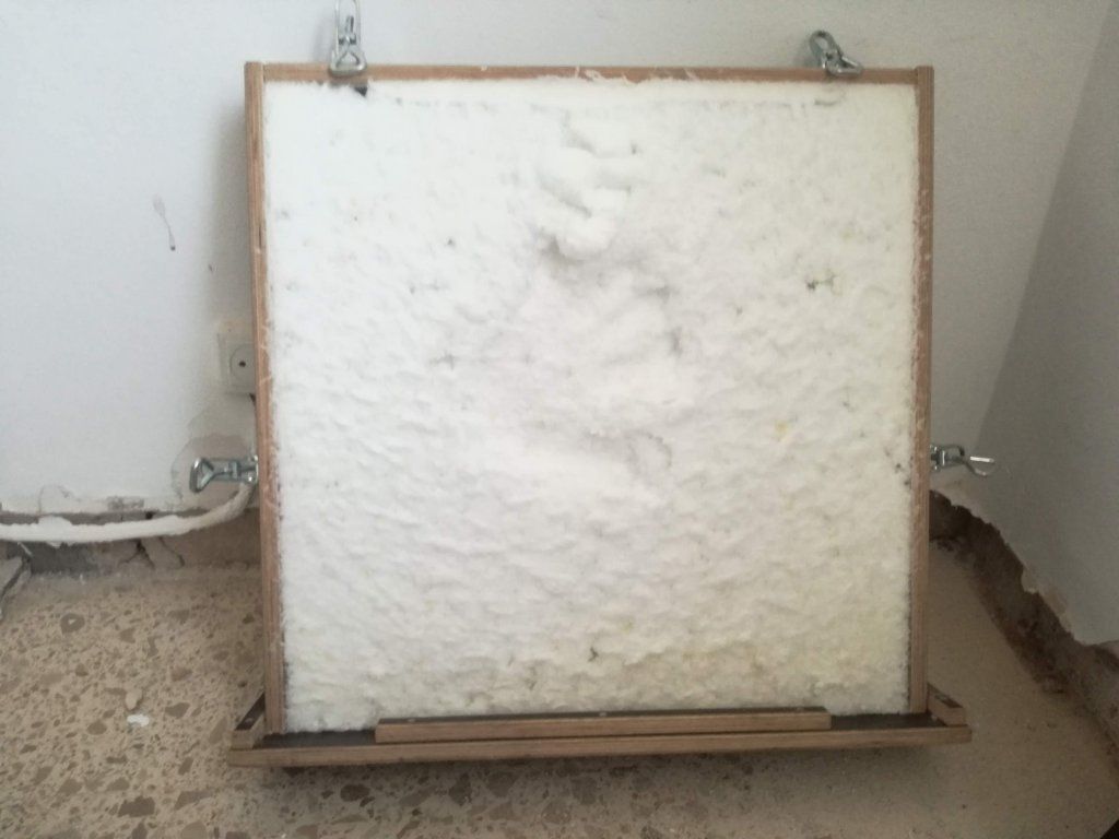 Panel de espuma blanca enmarcado en madera y montado en la pared.