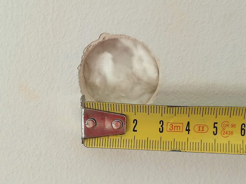 Un agujero en una pared blanca se mide con una cinta métrica
