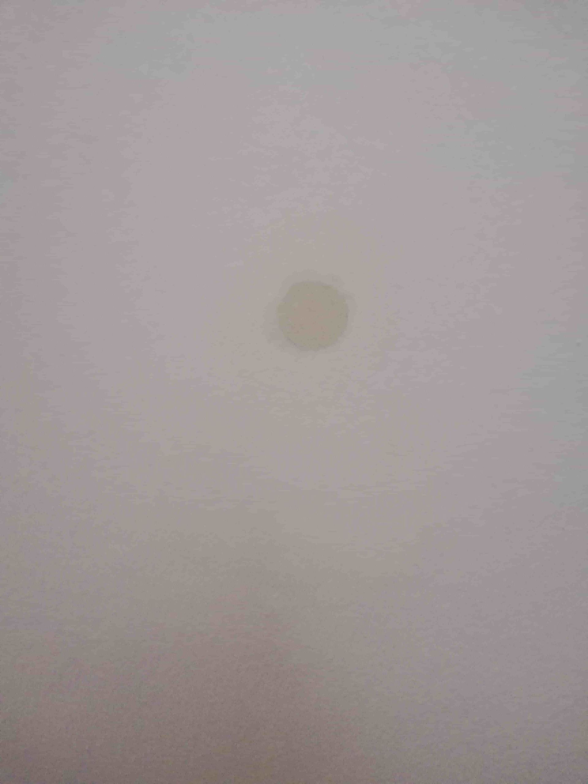 Una pequeña mancha de color claro centrada en un techo blanco.