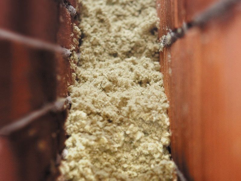 Material fibroso de color tostado que rellena el hueco entre dos tejas de color marrón rojizo.