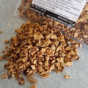 Montón de pequeñas virutas marrones, parecidas a la madera, con una bolsa transparente y una etiqueta al fondo.