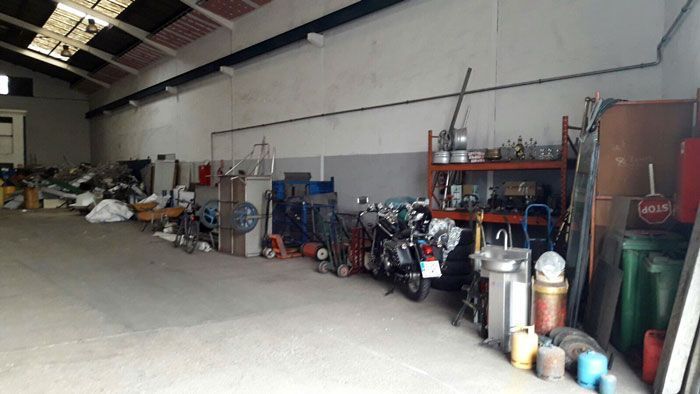 Interior de un taller desordenado. Herramientas, bicicletas y otros equipos se alinean contra las paredes del suelo de hormigón.