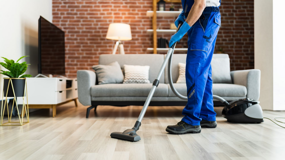 Professionnel nettoyant un sol avec un aspirateur dans un salon. 