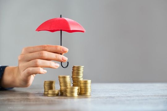 Eine Mitarbeiterin von Wolfgang Krupke hält einen Mini-Regenschirm über einige Stapel von Münzen.
