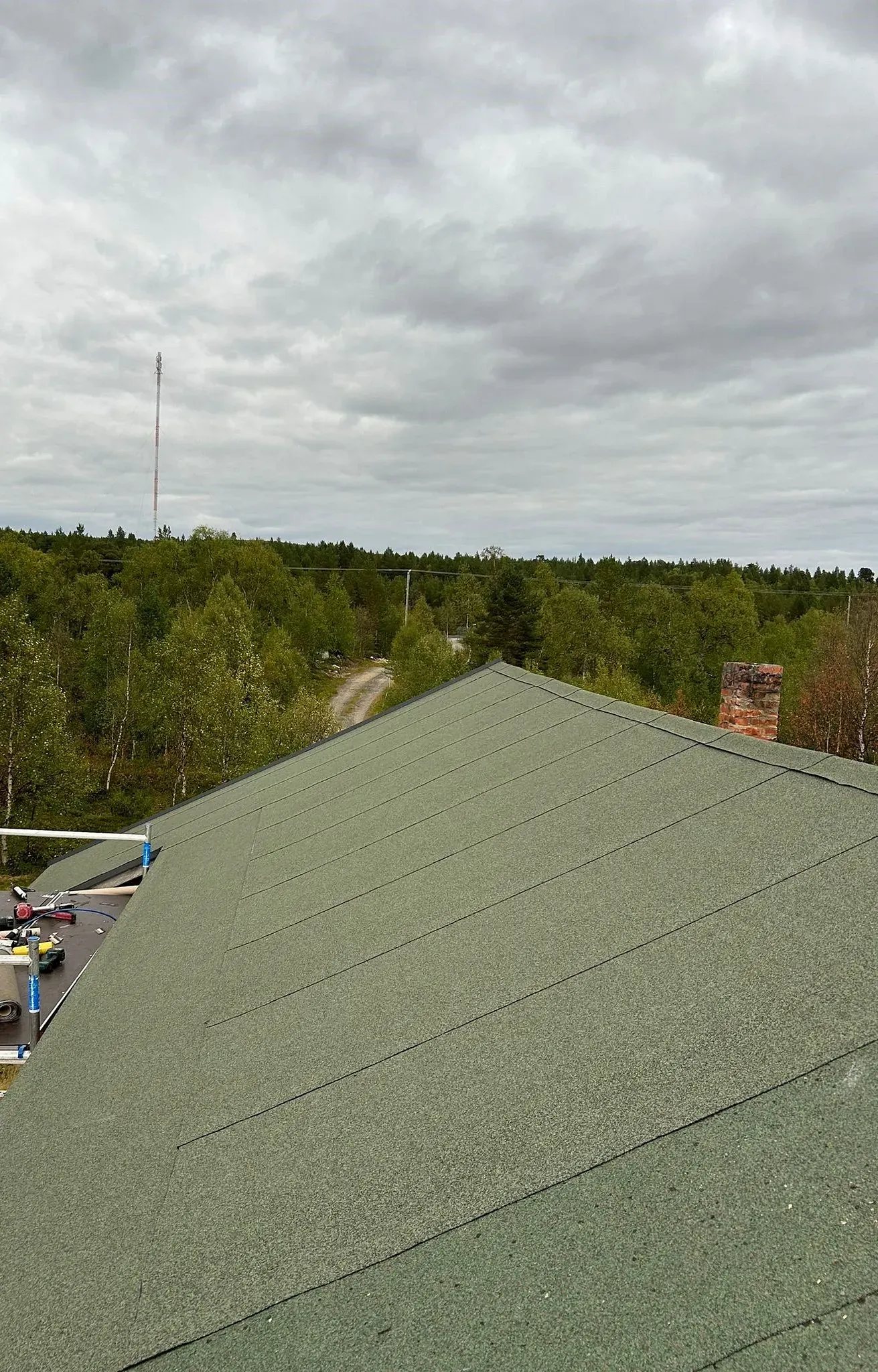Vihreä  katto, josta näkymät puihin, tielle ja pilviselle taivaalle.