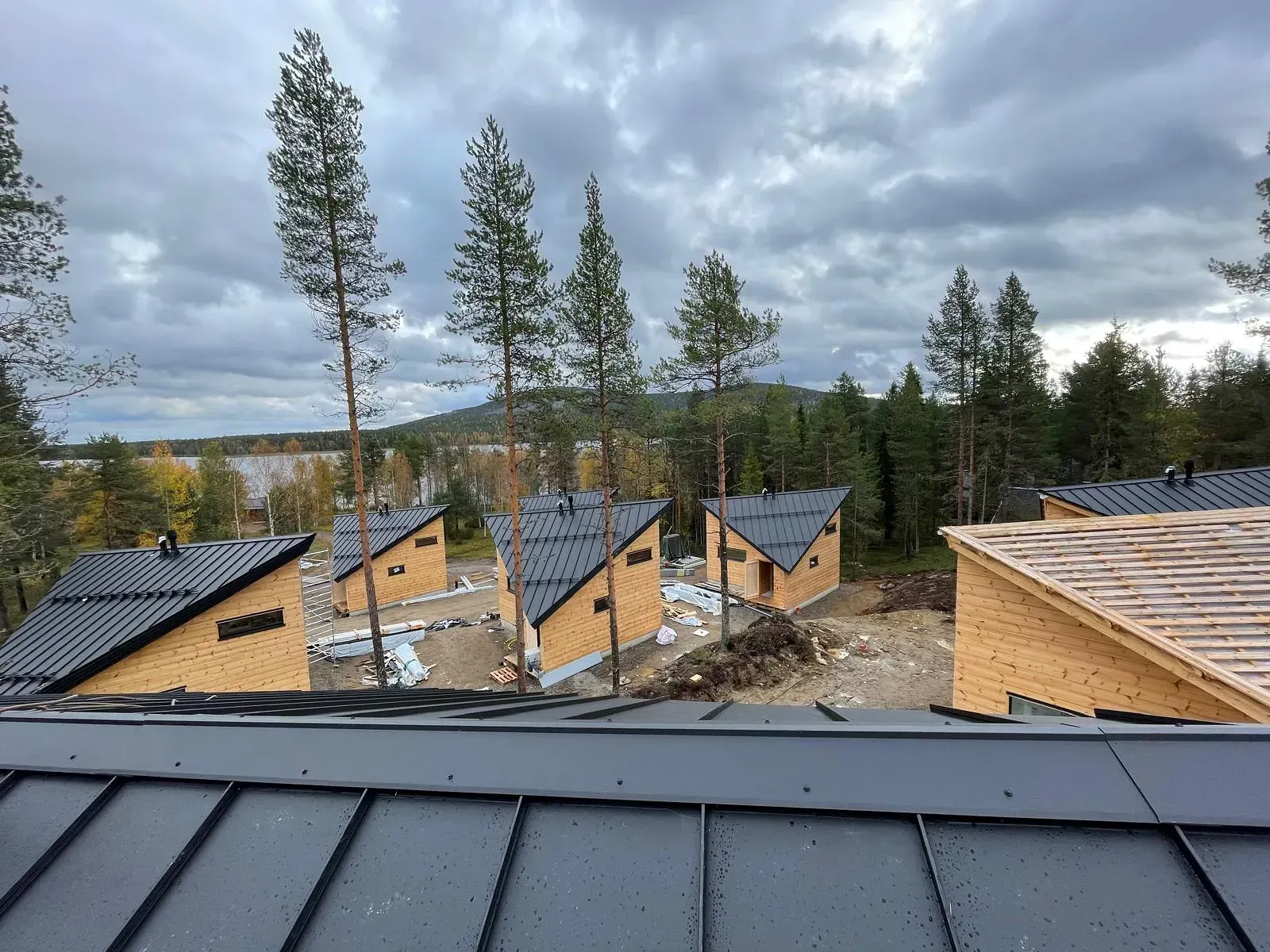Rakennustyömaa, jolla on useita pieniä puisia mökkejä pilvisen taivaan alla.