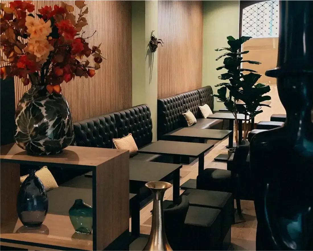 Acogedora sala con bancos acolchados con botones, mesitas y decoración floral en cálidos tonos de madera