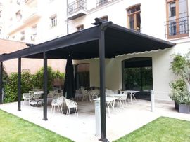 Un patio con mesas y sillas bajo un dosel negro.