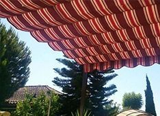 Una persona está sentada bajo un dosel de rayas rojas y blancas.