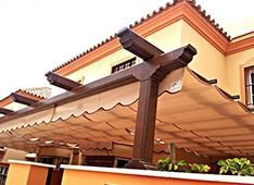 Una casa con una pérgola en el costado.