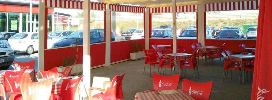 Un restaurante con sillas y mesas rojas con Coca Cola escrito en ellas.