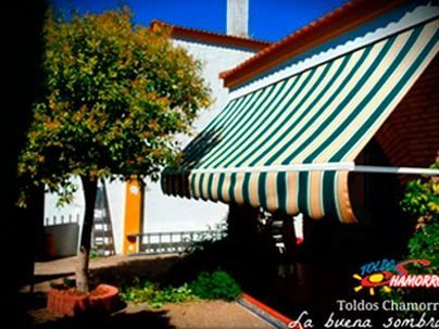 Un toldo de rayas verdes y blancas está en el costado de un edificio.