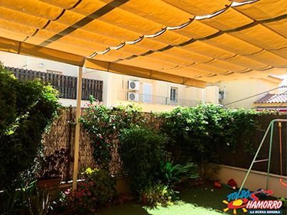 Un patio trasero con un toldo amarillo y un columpio.