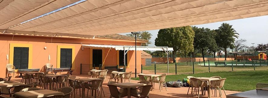 Un patio con mesas y sillas bajo un dosel.