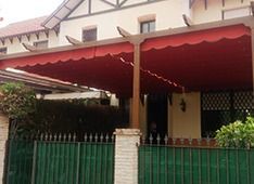 Una casa con un toldo rojo sobre el porche y una valla verde.