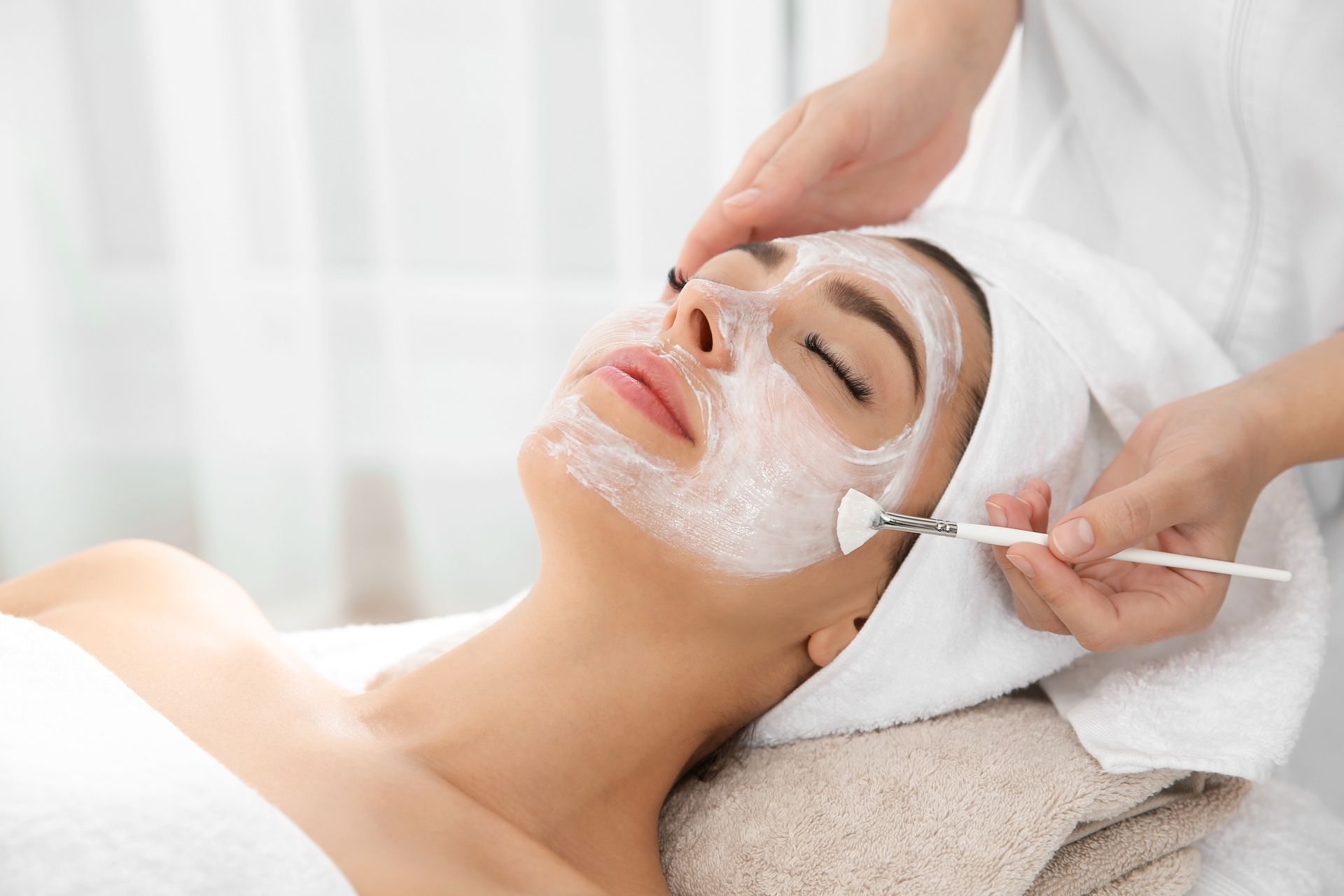 Mujer recibiendo un tratamiento facial con una mascarilla aplicada en un spa.