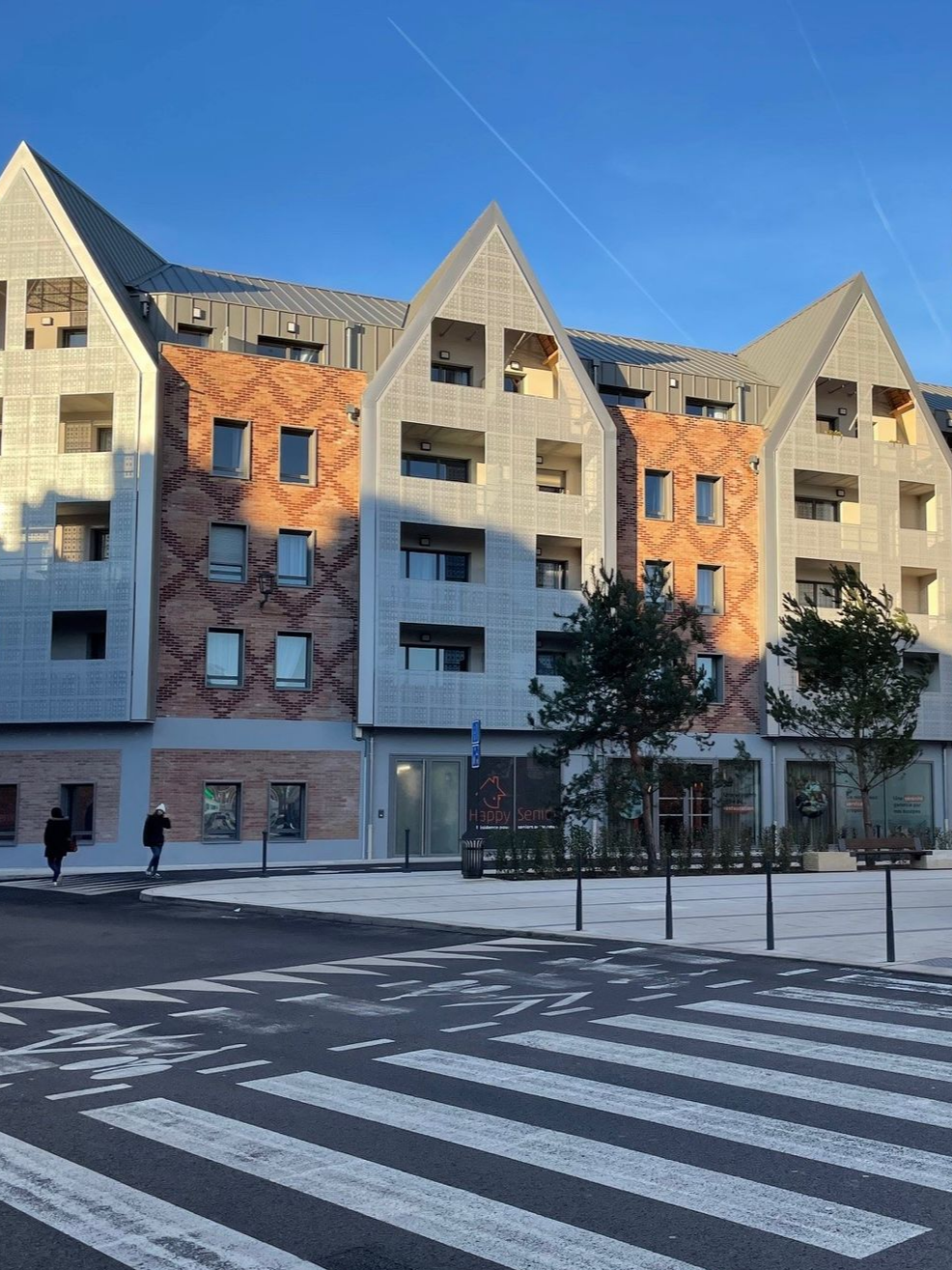 Immeuble d'appartements moderne avec passage piéton devant.