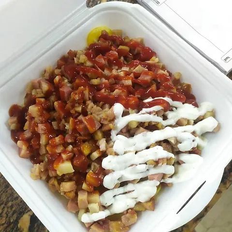 Un recipiente de poliestireno lleno de comida, incluyendo ketchup y crema agria.