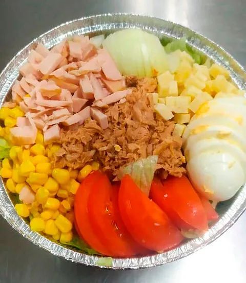 Un recipiente de papel de aluminio lleno de una variedad de verduras y carnes.