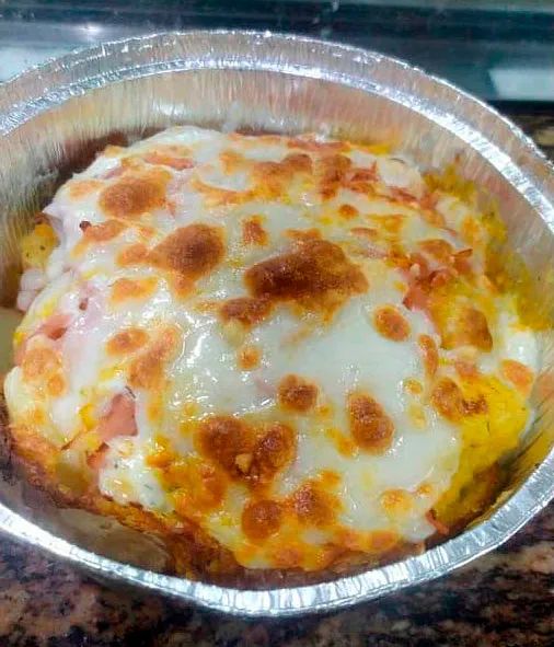 Un primer plano de un recipiente de aluminio lleno de comida sobre una mesa.