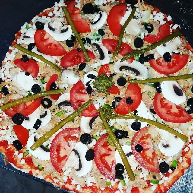 Una pizza con tomates, champiñones y aceitunas.