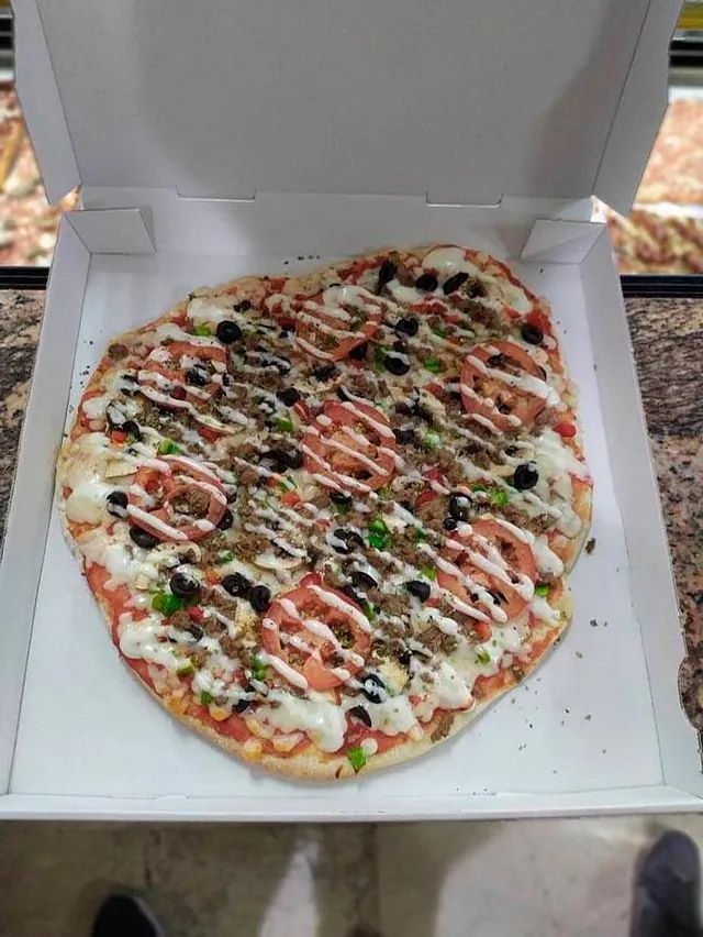 Una pizza está en una caja de cartón sobre una mesa.