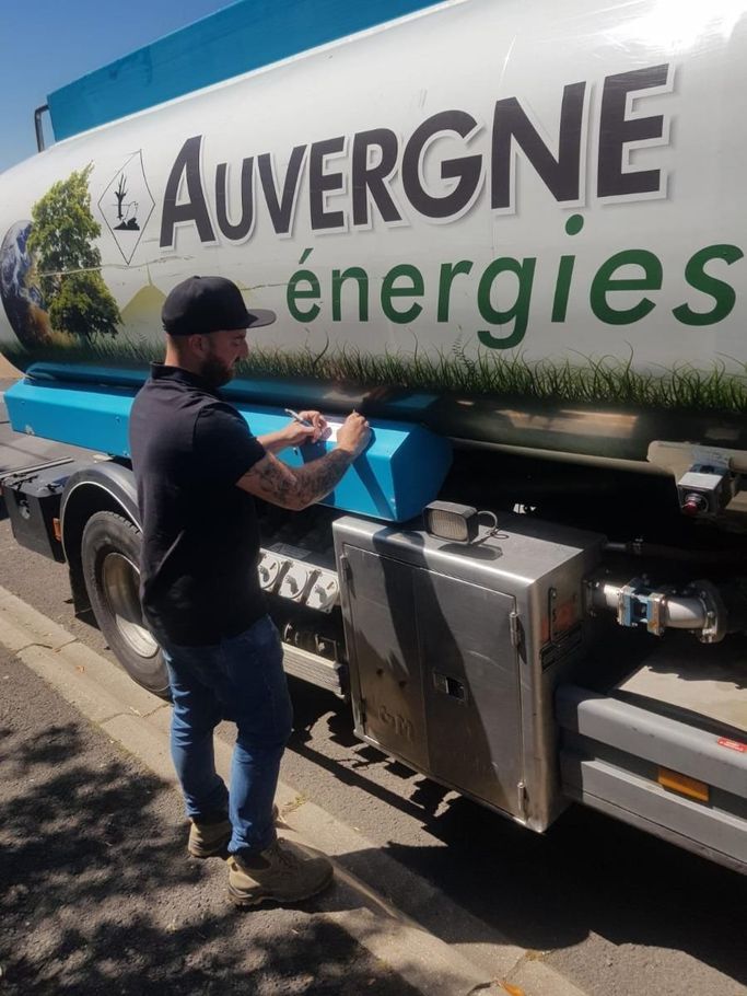 Un technicien qui remplit une feuille devant son camion de livraison de combustible
