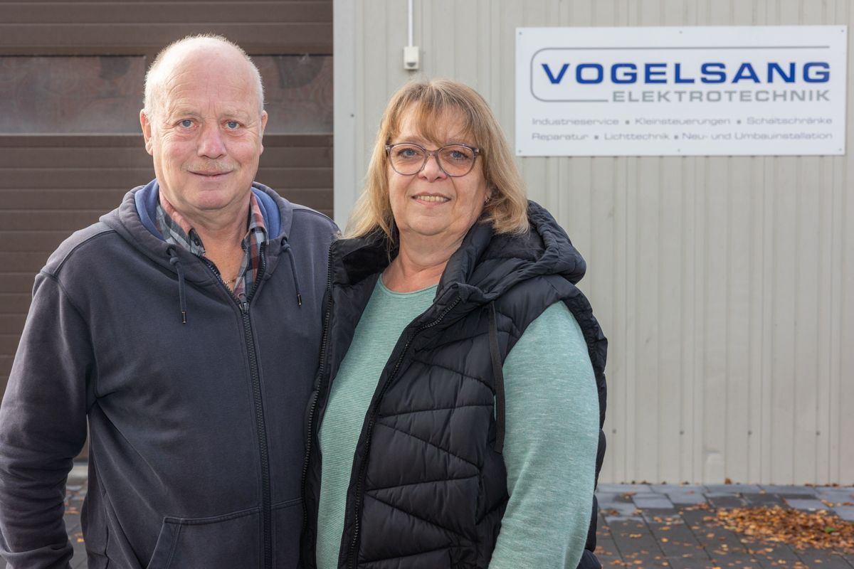 Ein Mann und eine Frau stehen vor einem Vogelsang Elektrotechnik-Schild