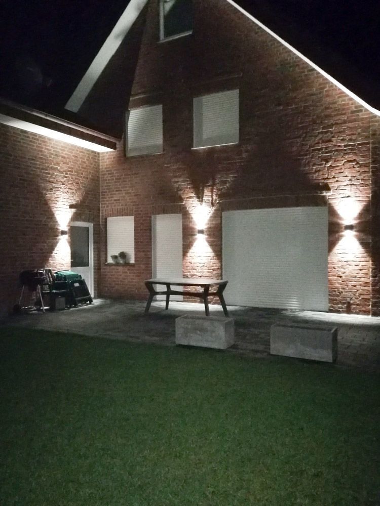 ein Backsteinhaus mit einem weißen Garagentor und einem Picknicktisch