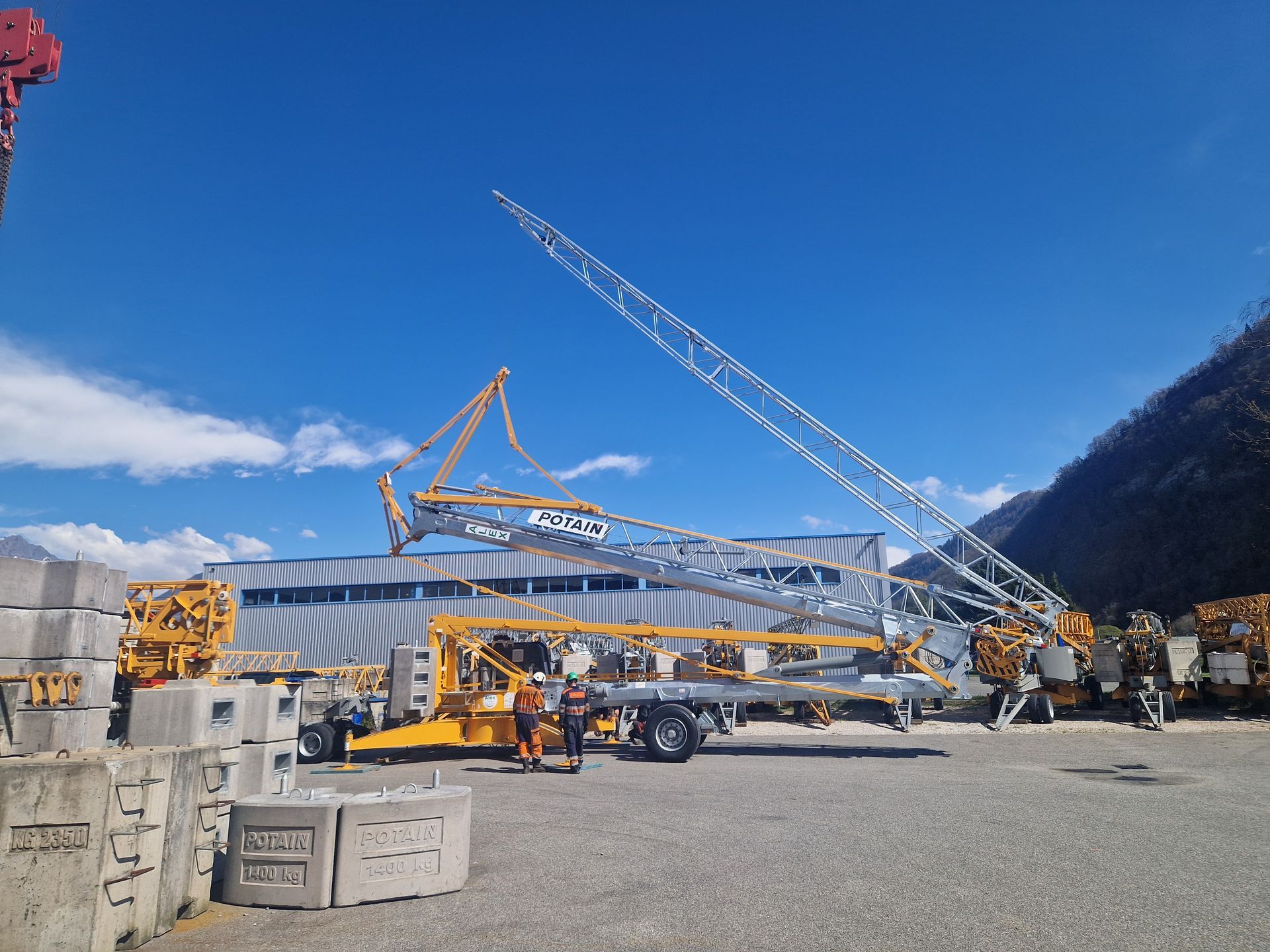 Chantier de construction avec une grue assemblant une haute tour sur fond de ciel bleu.