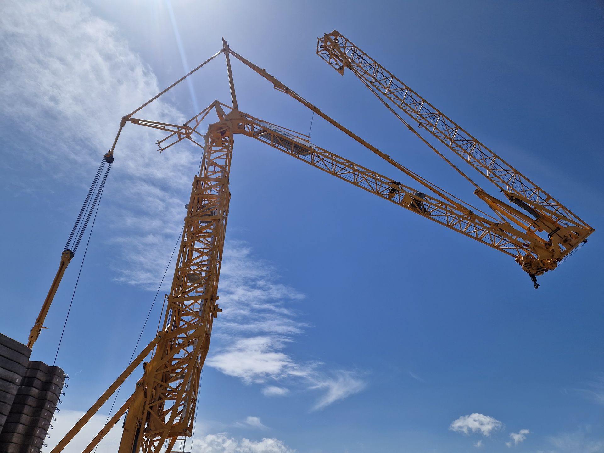 Grue de chantier jaune, ciel bleu avec nuages en arrière-plan.