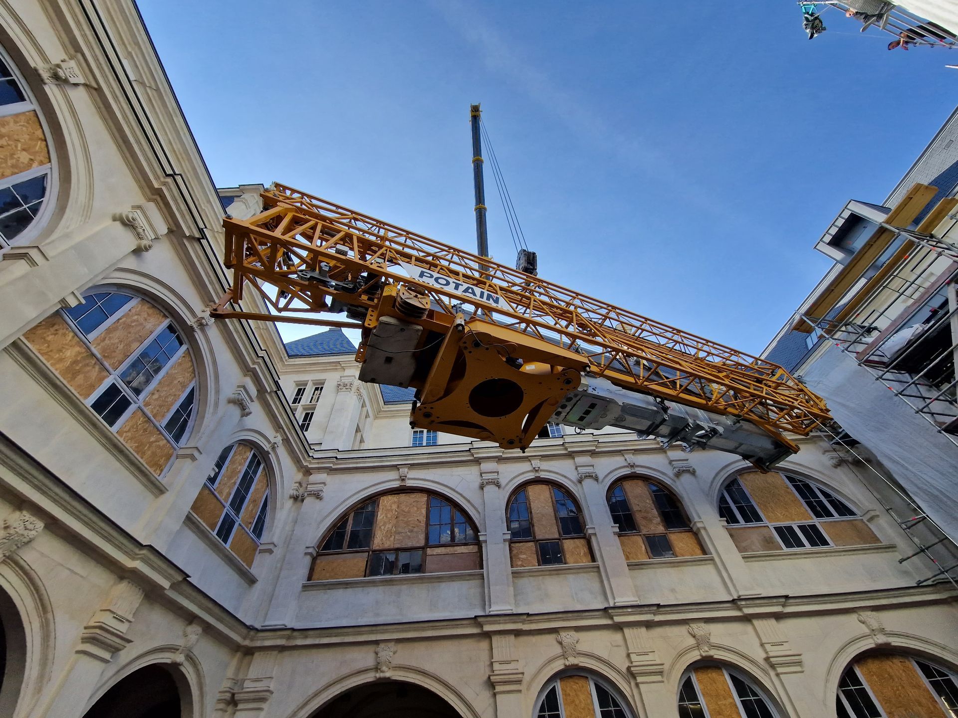 Un bras de grue jaune surplombe un bâtiment historique.