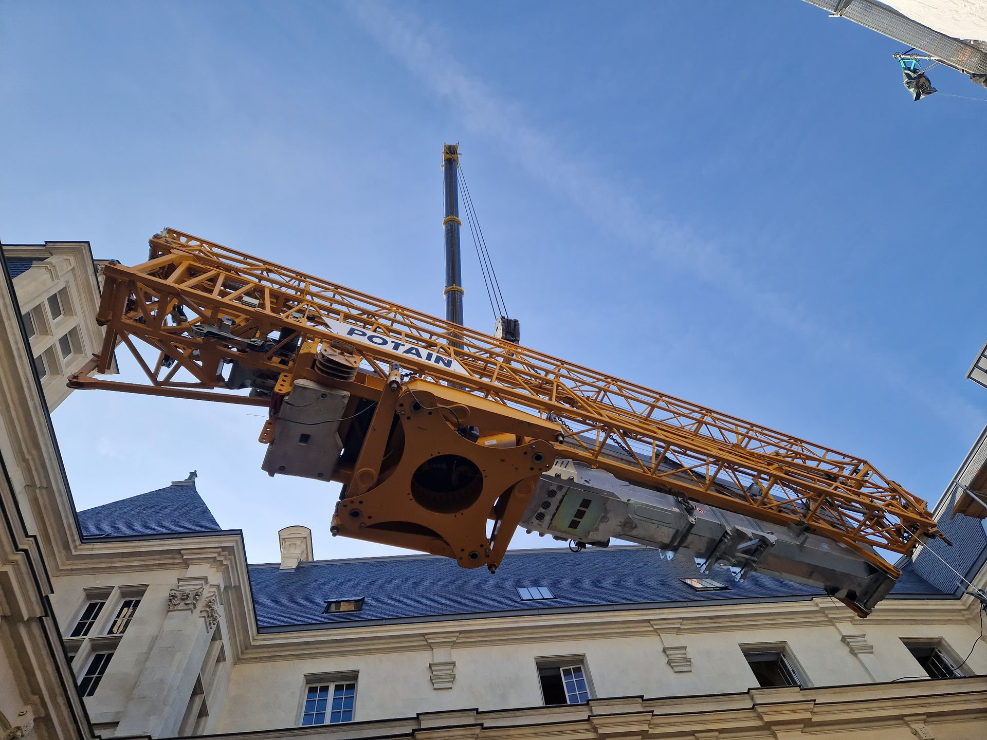 Une grue de chantier jaune surplombe un bâtiment.