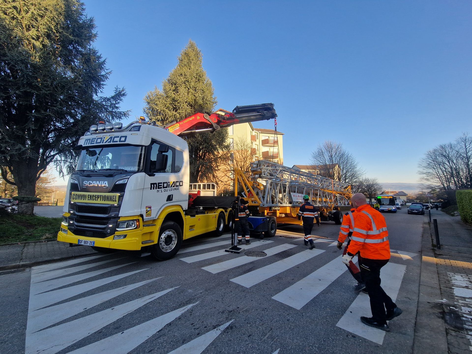 Un camion transportant une grue roule sur un passage piéton.