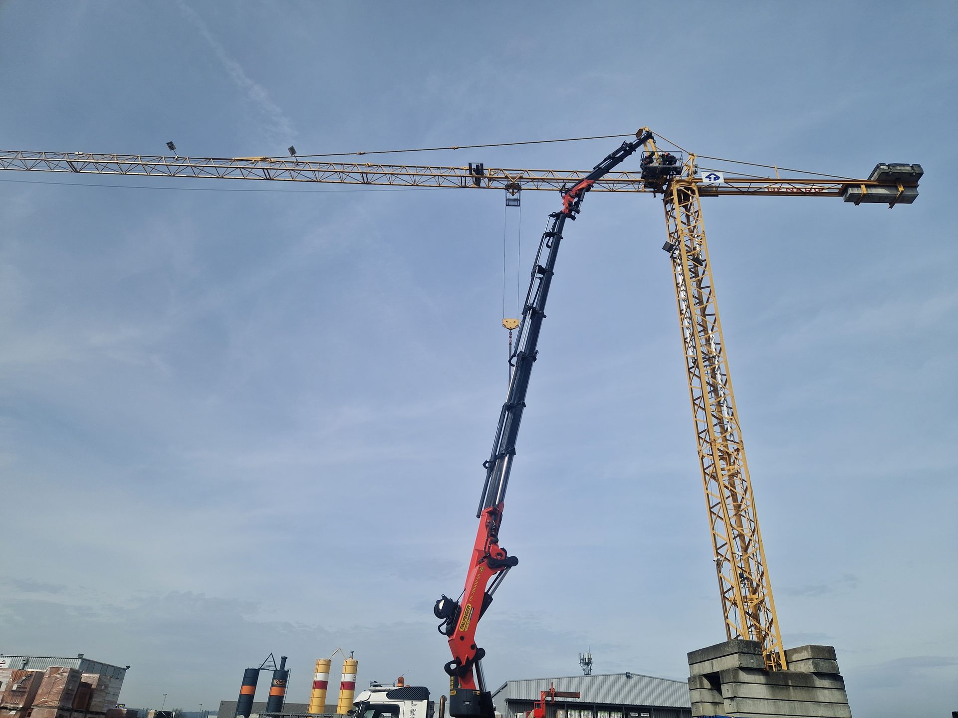 Une grande grue de chantier jaune et une plus petite grue rouge.