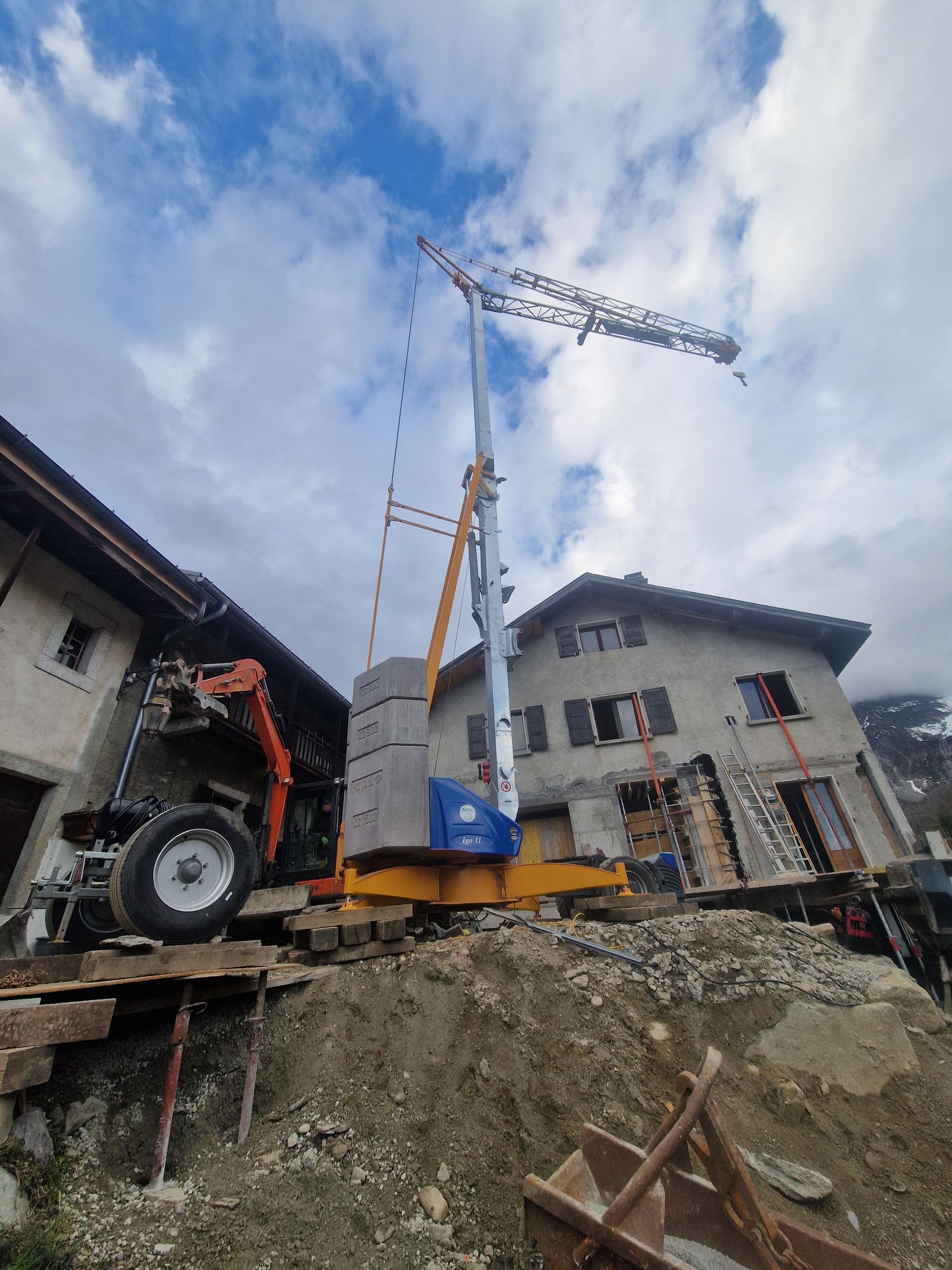 Grue sur un chantier de construction entre deux bâtiments. Terre et débris entourent la base de la grue.