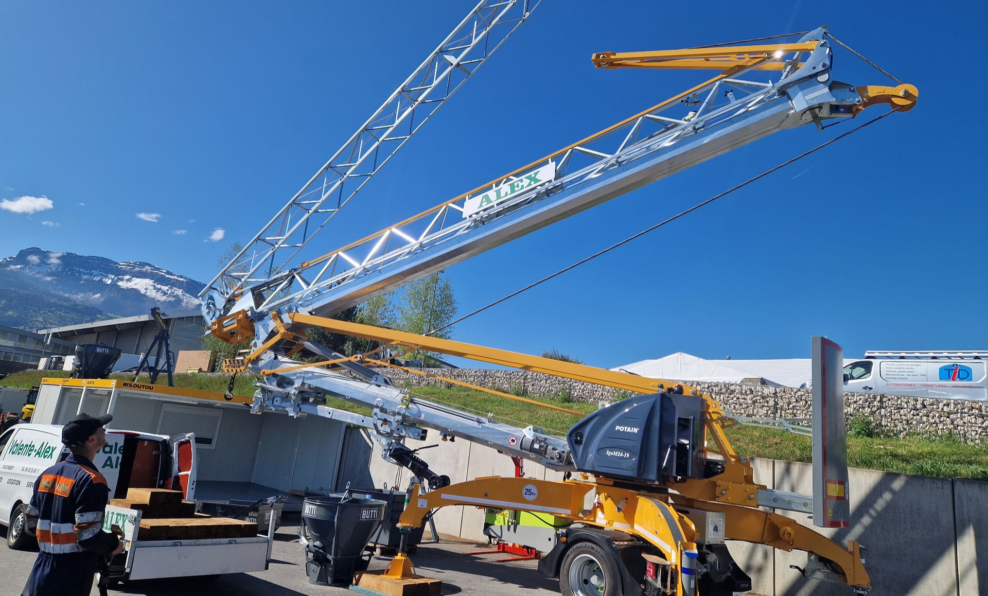 Une grue Potain en cours de montage, montagnes en arrière-plan.