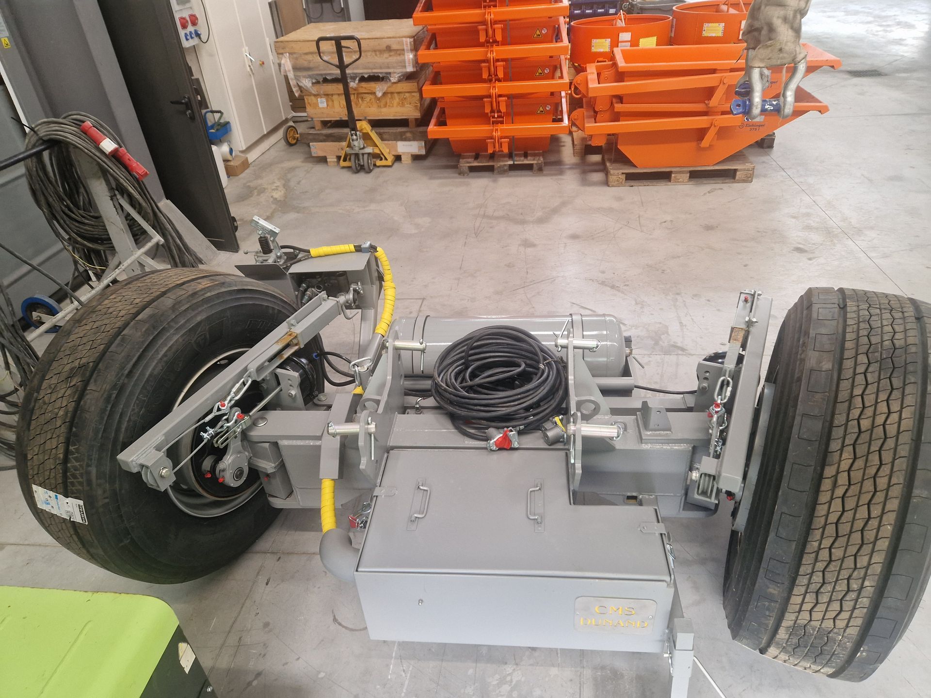 Un châssis de remorque gris avec de gros pneus dans un entrepôt.