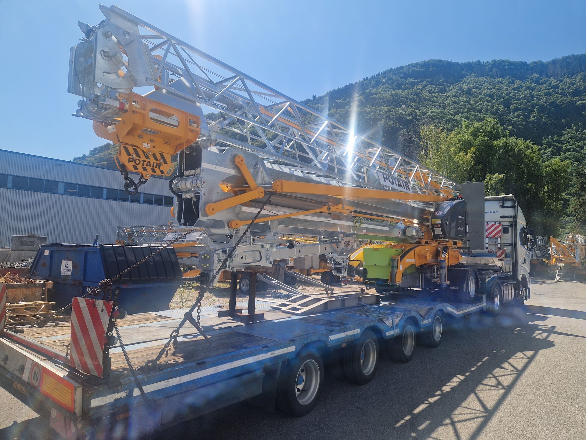 Grue Potain jaune et argent, sur un camion plateau.