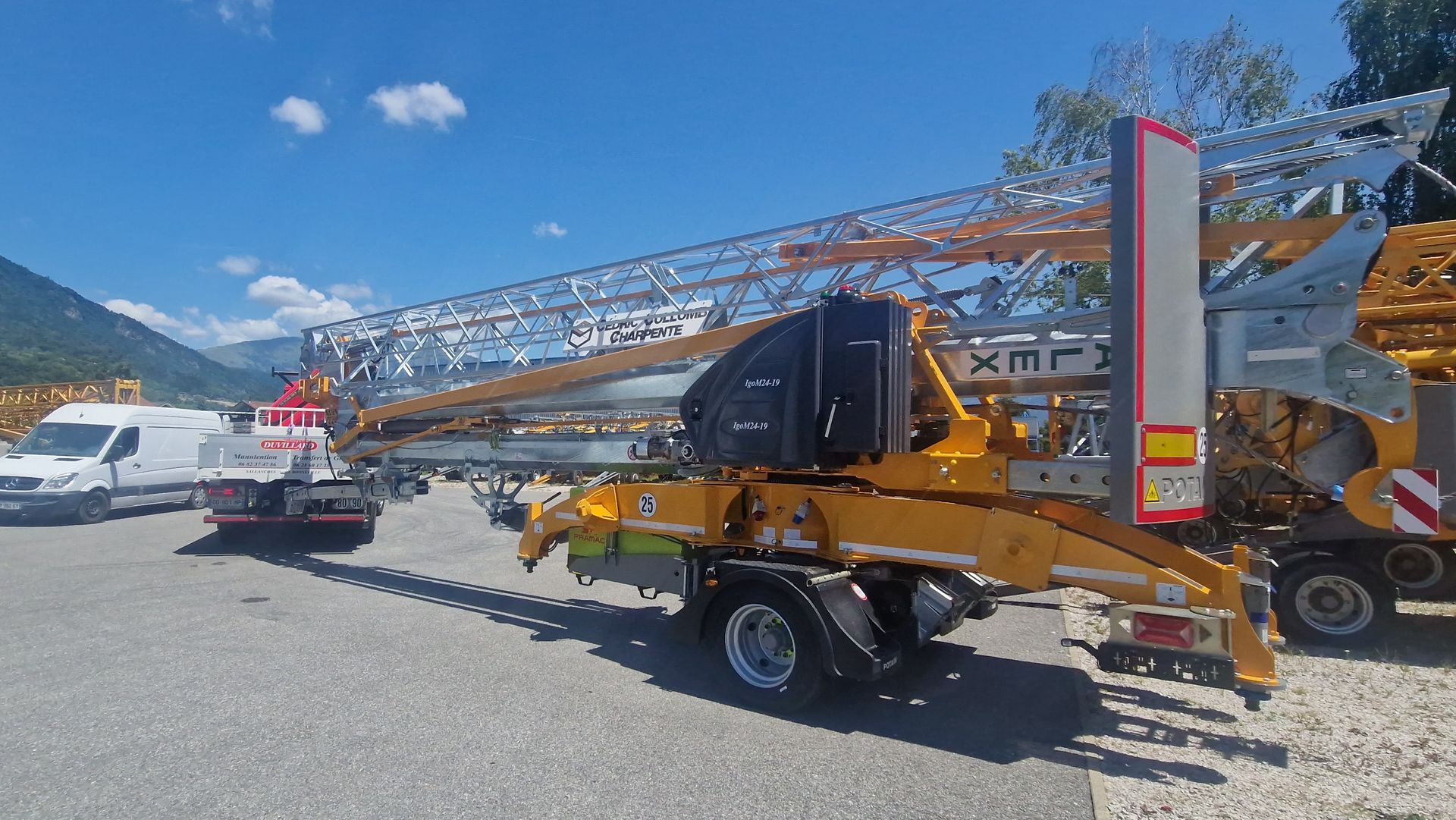 Des pièces de grue jaunes sur une remorque, avec des montagnes en arrière-plan.