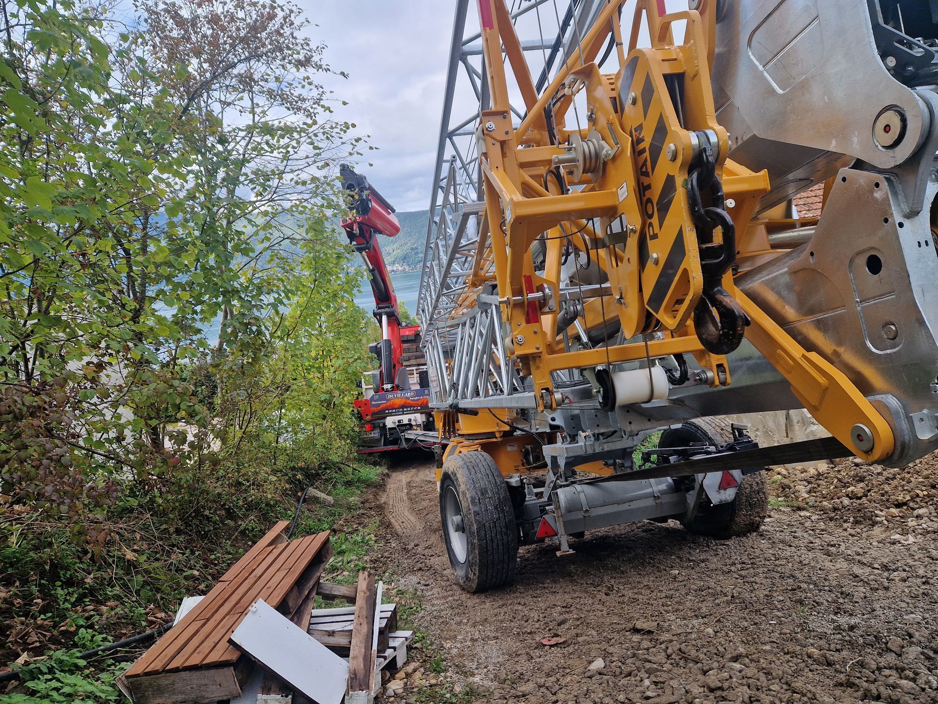Des engins de chantier circulent sur un chemin de terre.