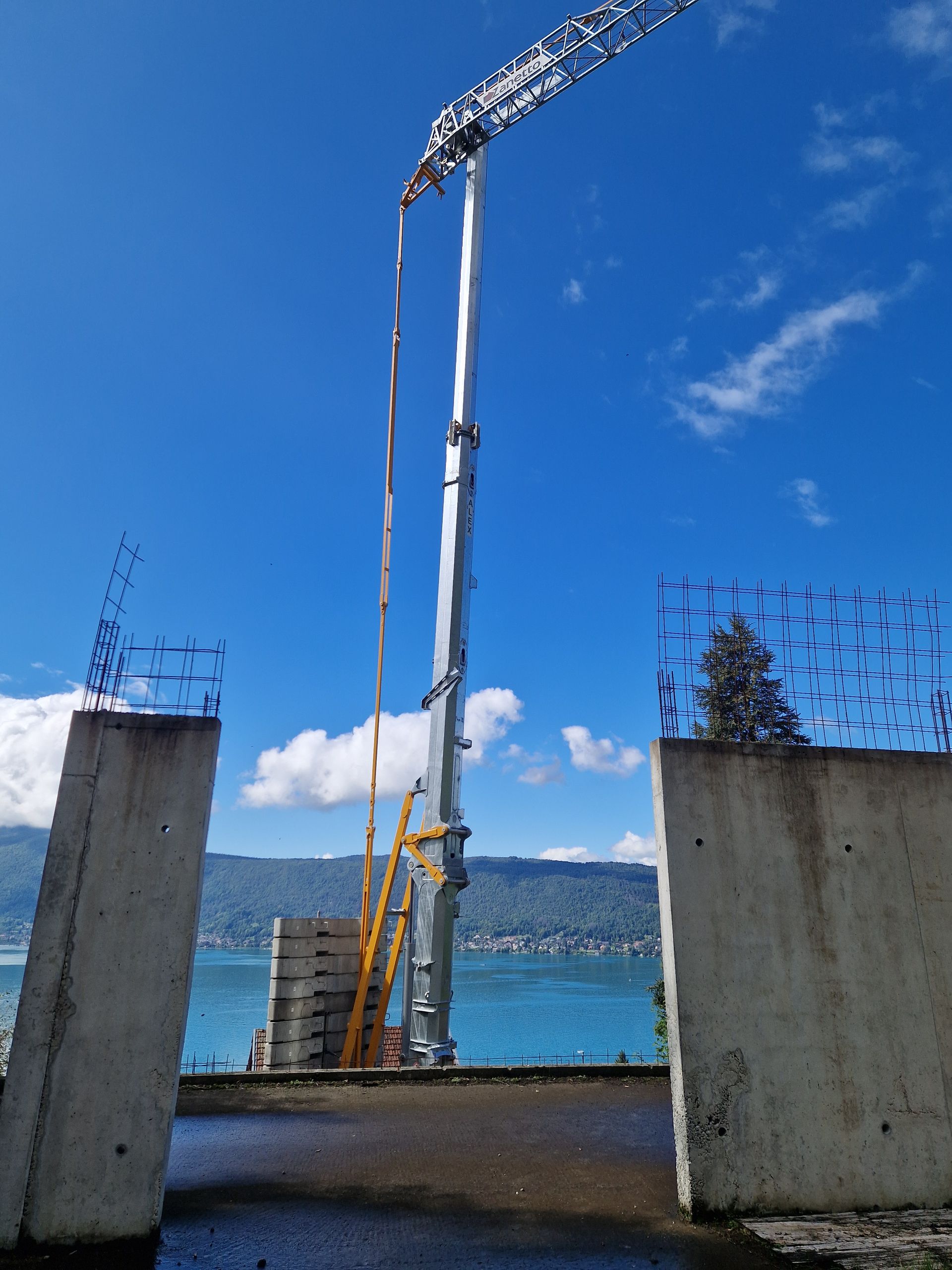 Une grande haute grue de chantier se dresse au-dessus de structures en béton.