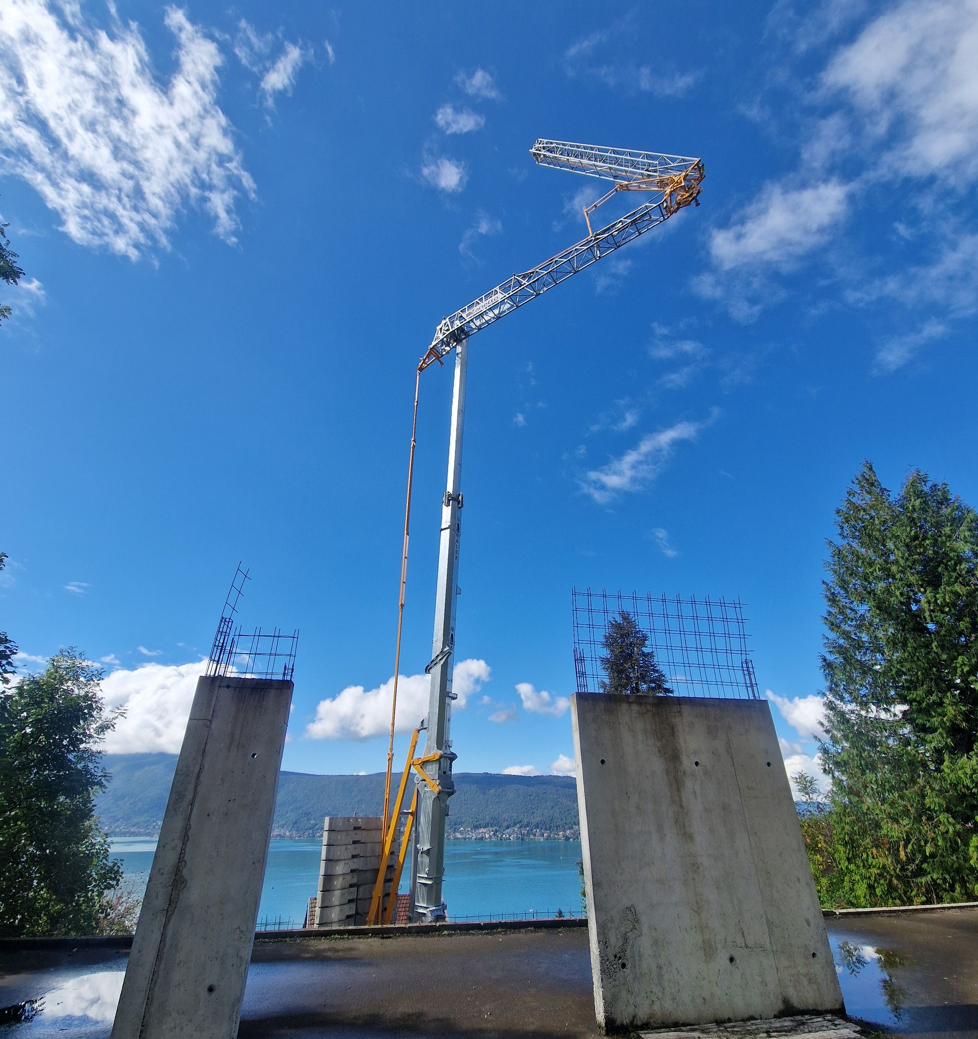 Chantier de construction avec coffrages en béton, un grand bras de pompe s'élevant vers le ciel.